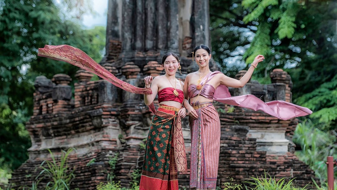 Women in traditional attire at ancient ruins during the Ancient City & Erawan Museum tour.
