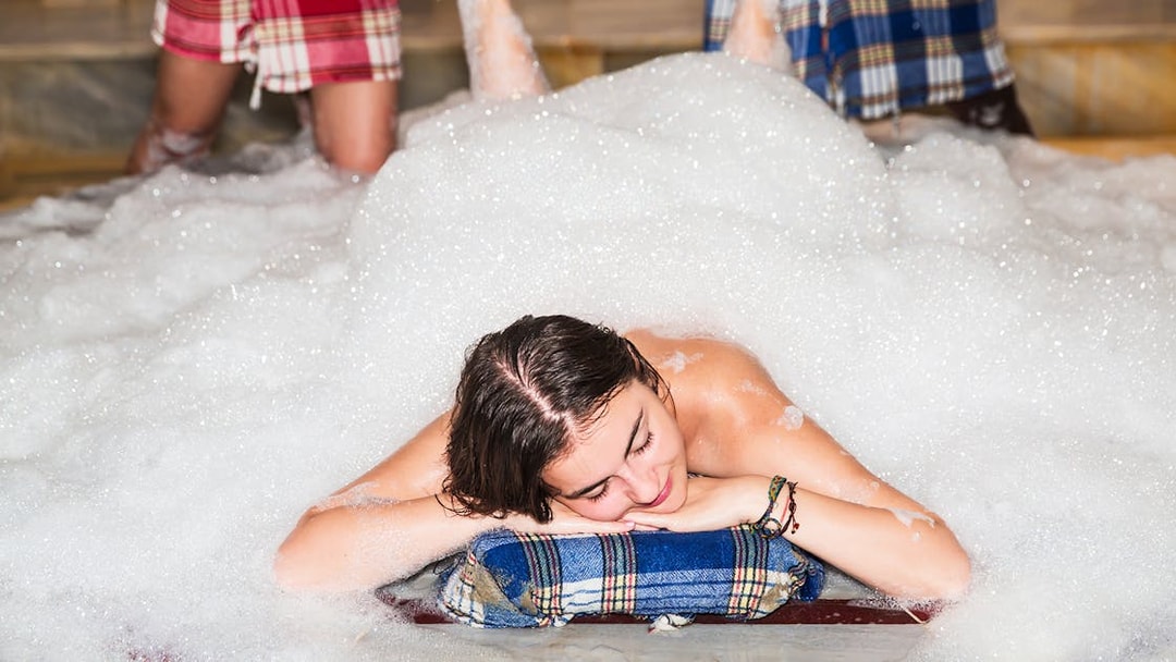Traditional Turkish bath in Antalya with foam massage on marble surface.