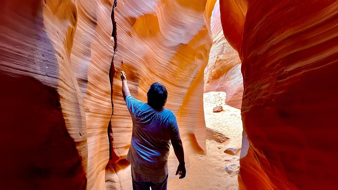 Visitor exploring narrow sandstone walls of Antelope Canyon X.