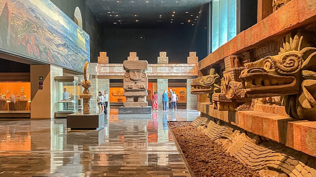 Ancient stone sculptures and visitors inside the Anthropology Museum, Mexico.