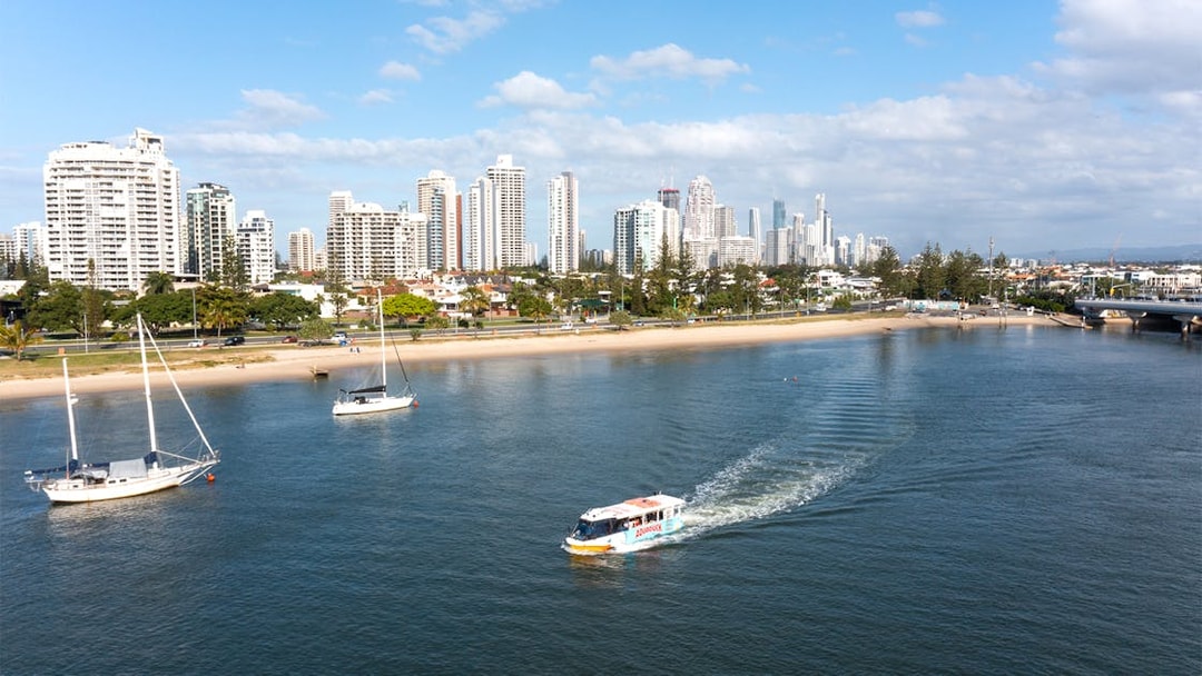 Aquaduck boat cruising on a river with city skyline in the background, Gold Coast.
