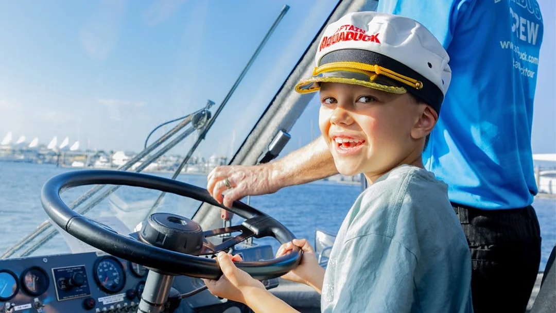 Child steering Aquaduck boat during Gold Coast river cruise.