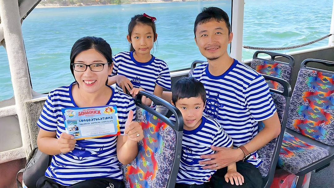 Family on Aquaduck Sunshine Coast tour holding certificate, seated on river cruise boat.