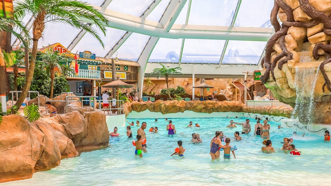 Tourists enjoying the wave pool at Aqualibi indoor water park.