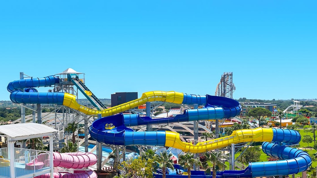 Colorful water slides at Aquashow Water Park, Portugal, with lush greenery in the background.