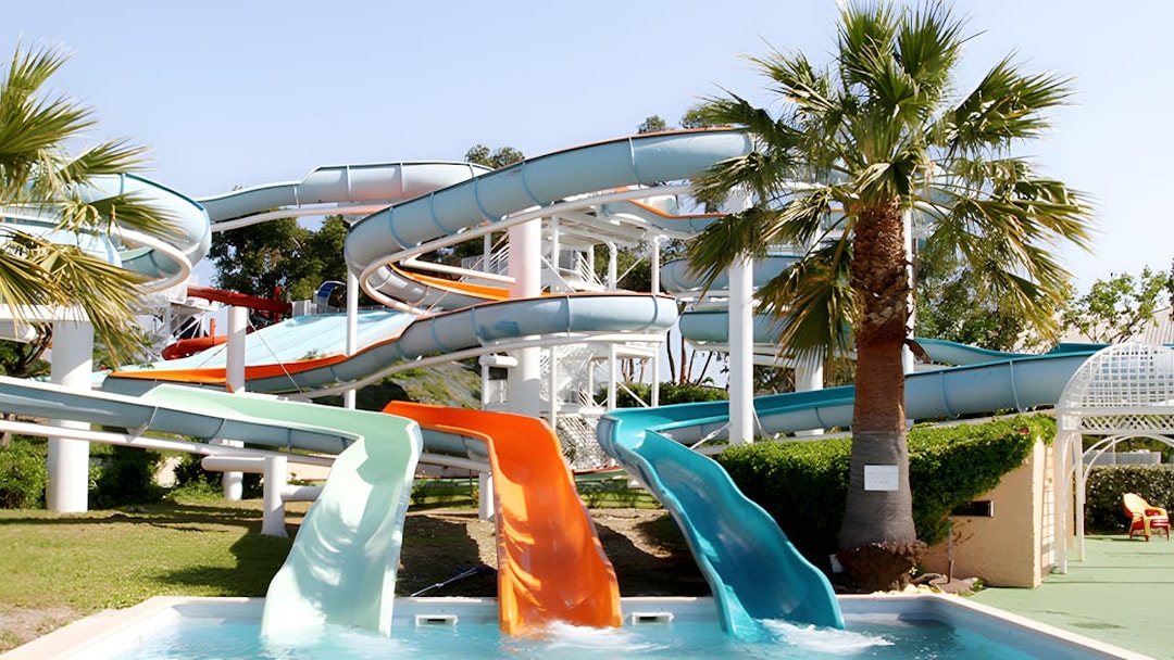 Water slides at Aquasplash Antibes, France, with palm trees and a pool.