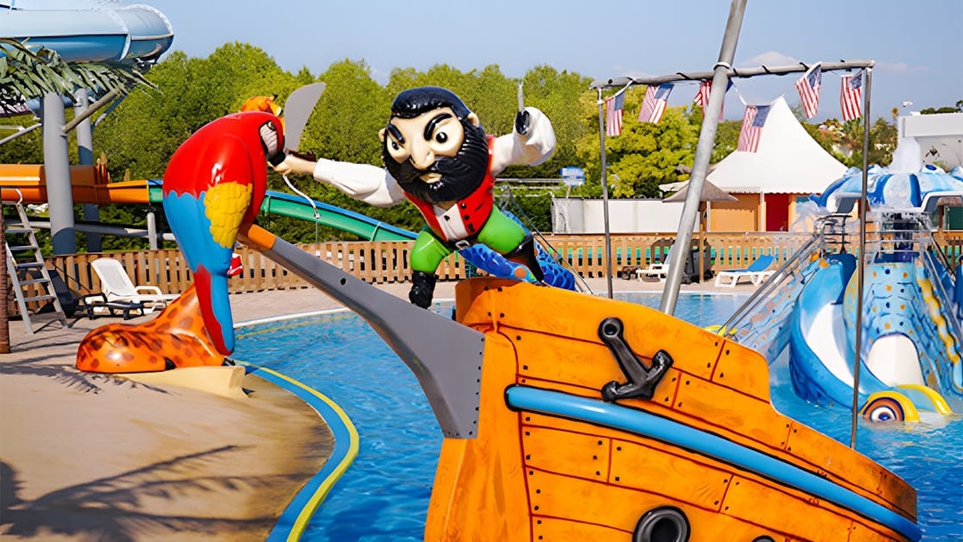 Pirate-themed water slide at Aquasplash Antibes with colorful parrot statue.