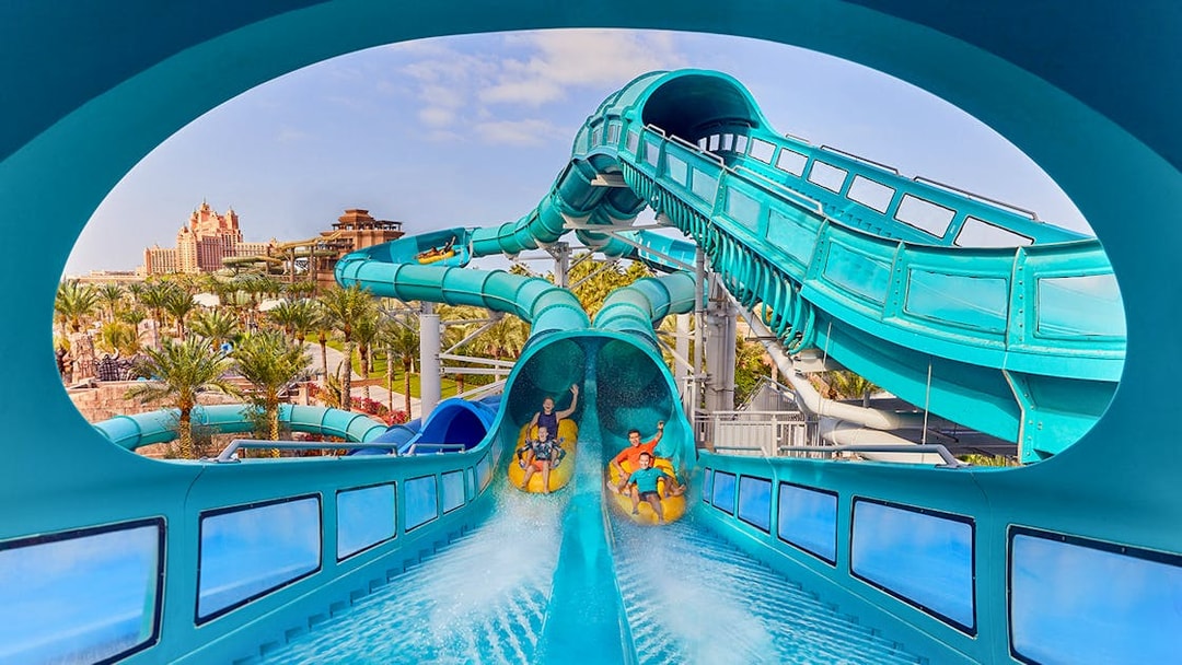 Riders on Medusas Lair water slide at Atlantis, The Palm, Dubai with resort view.