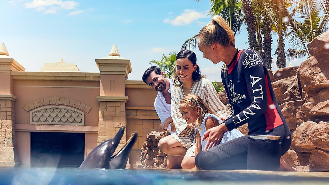 Family interacting with dolphins at Atlantis, The Palm, Dubai.
