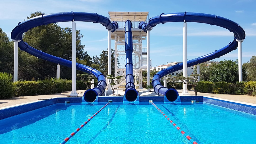 Water slides at Aquopolis Costa Daurada leading into a clear blue pool.