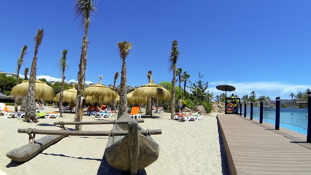 Aquopolis Costa Daurada beach area with straw umbrellas and sun loungers.