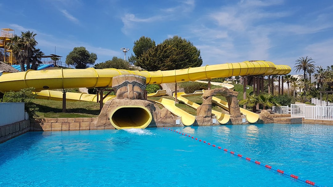 Water slides at Aquopolis Costa Daurada, Spain, leading into a clear blue pool.