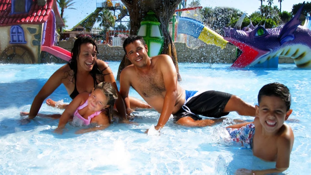 Family enjoying the water at Aquopolis Torrevieja with colorful slides in the background.