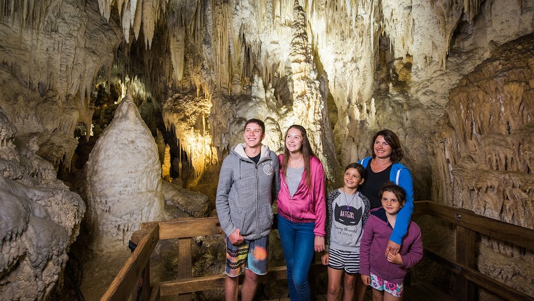 Guided tour group exploring limestone formations inside Aranui Cave, Waitomo, New Zealand.