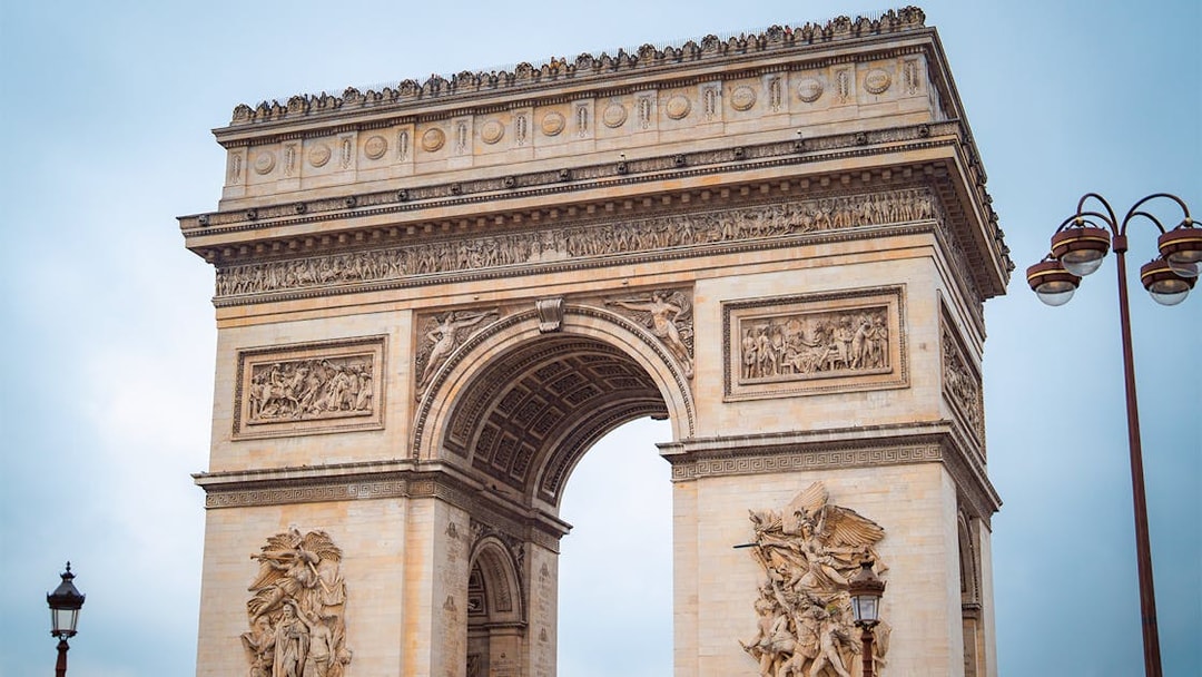 Arc de Triomphe in Paris with detailed sculptures, view from street level.