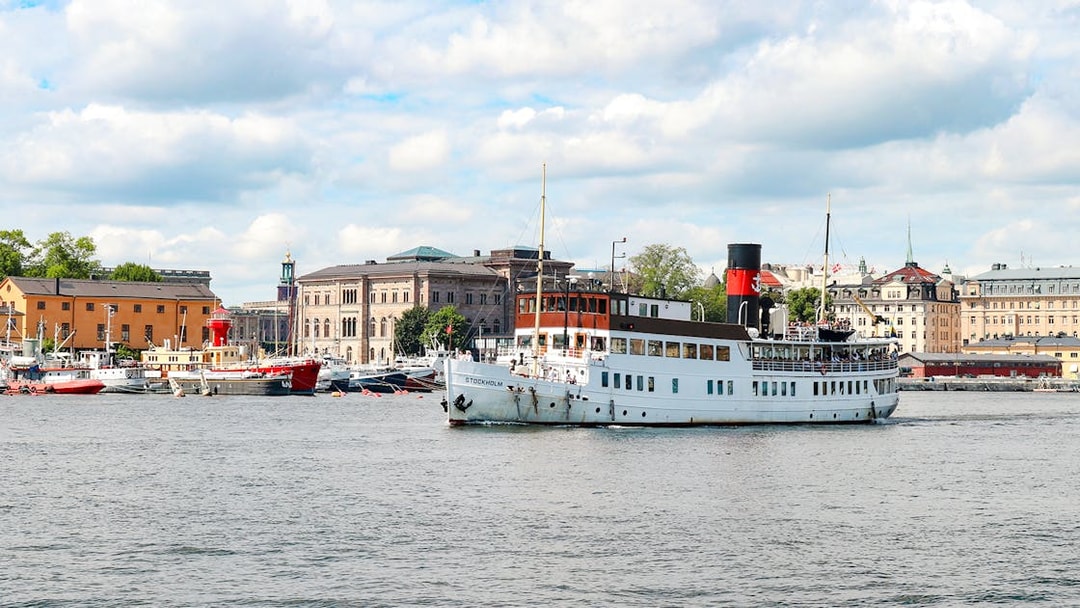 Cruise ship sailing near Stockholm waterfront with historic buildings in view.