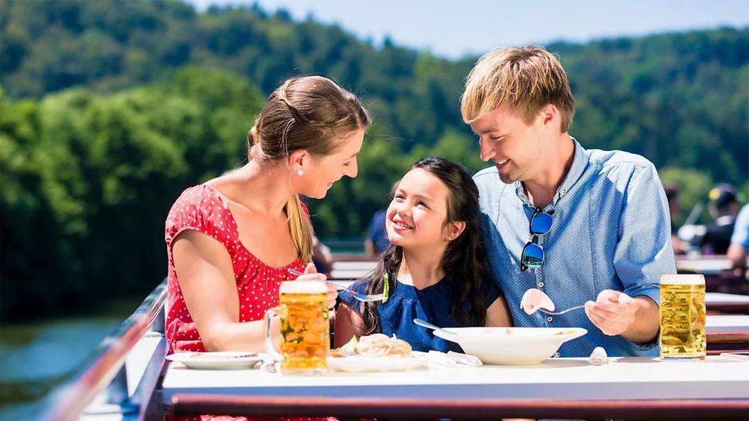 Family enjoying lunch on a Koblenz river cruise with scenic views.