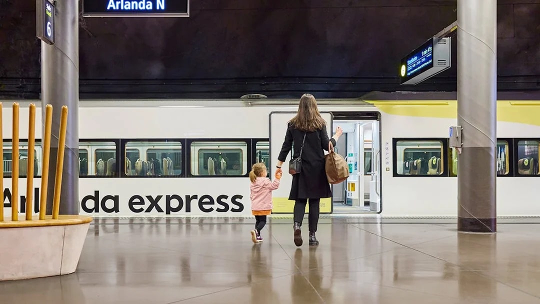 Woman and daughter boarding Arlanda Express train at Stockholm station.