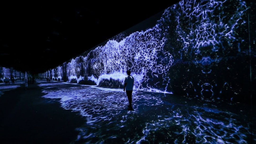 Person walking through ARTE Museum Dubai's Starry Beach exhibit with digital waves.