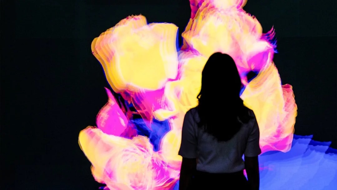 Silhouette of a person viewing vibrant digital roses at Arte Museum Dubai's Flower Odyssey exhibit.