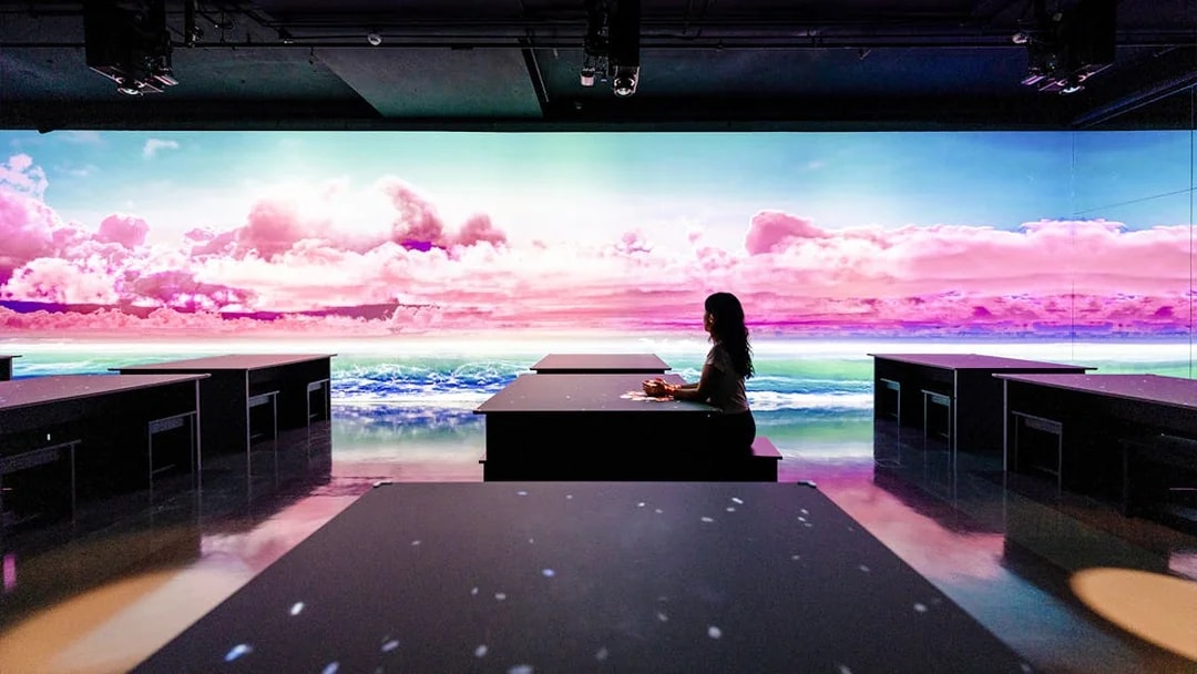 Person seated at ARTE TEA BAR, Arte Museum Dubai, with vibrant digital ocean and sky display.