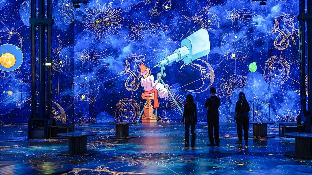 Immersive digital exhibition of "The Little Prince" at Atelier des Lumières, Paris, with celestial projections.
