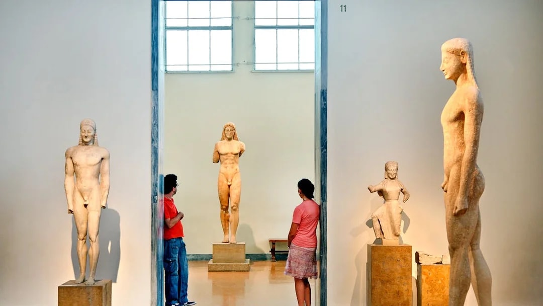 Visitors viewing ancient Greek statues at Athens National Archaeological Museum.