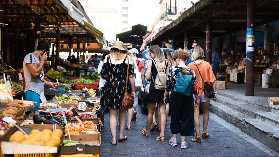 Tourists exploring a vibrant market in Athens during a food tour.