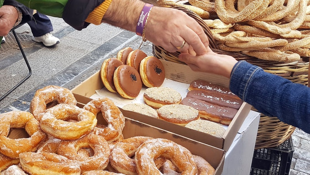 Street vendor exchanging Greek pastries during Athens food tour.