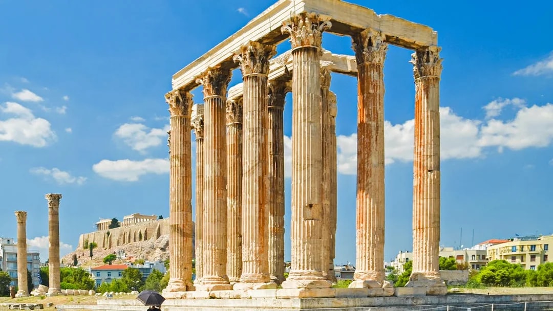 Temple of Olympian Zeus ruins in Athens with Acropolis in the background.