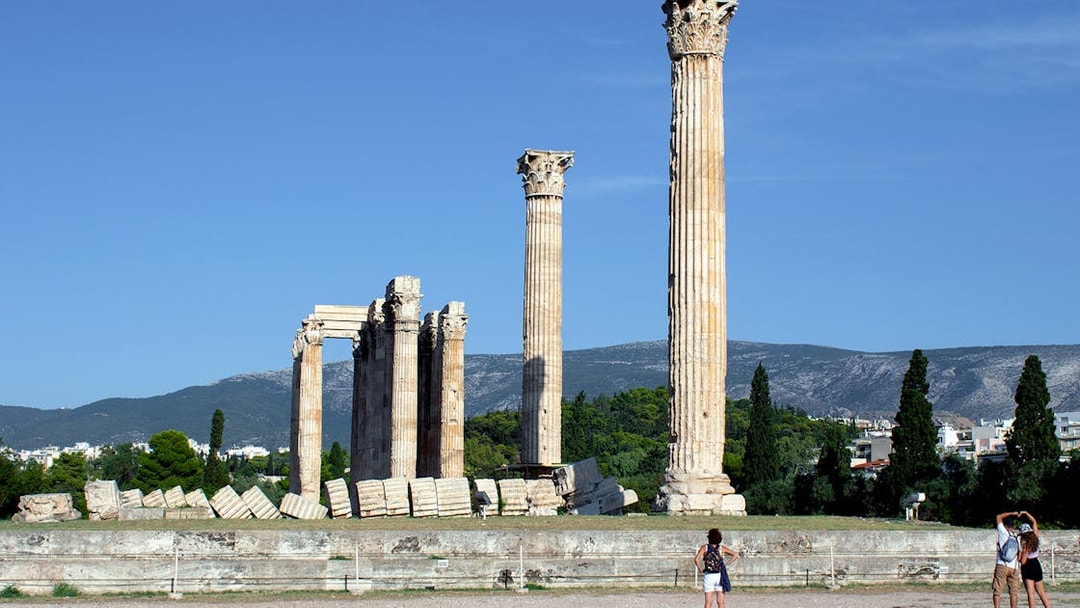 Ancient Temple of Olympian Zeus ruins in Athens with tourists exploring.