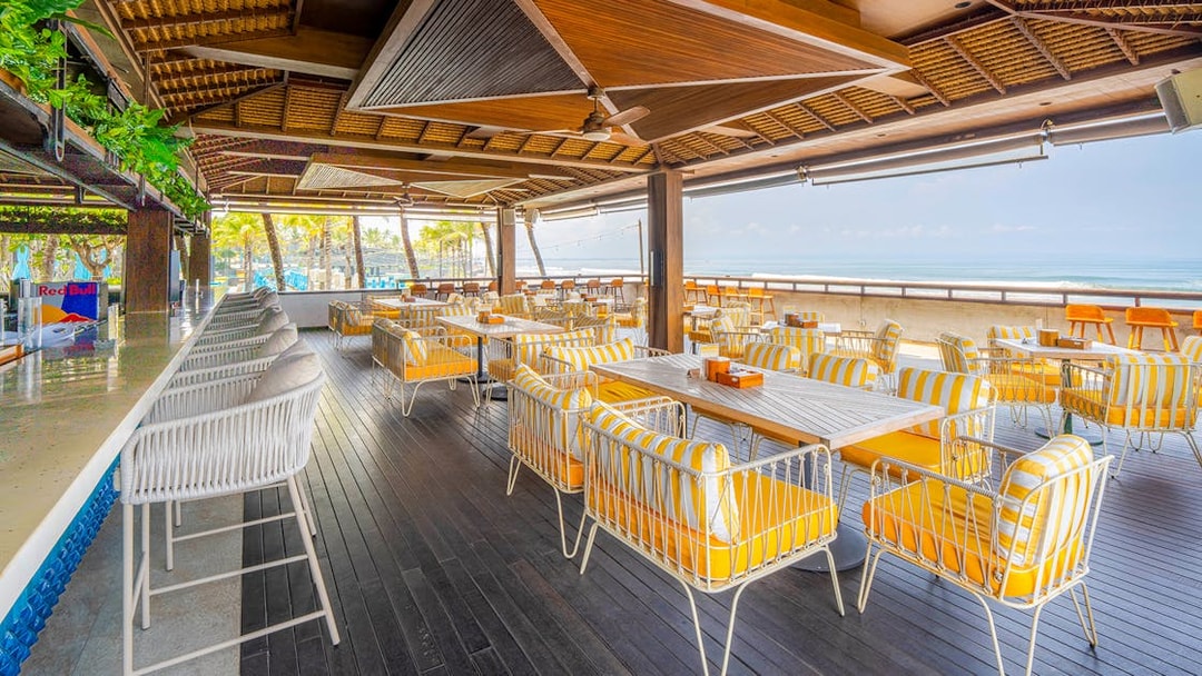 Outdoor seating area at Atlas Beach Club with ocean view and striped chairs.