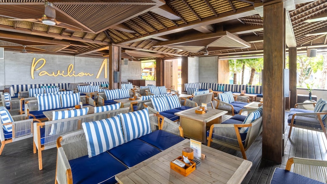 Atlas Beach Club seating area with striped cushions and wooden tables.
