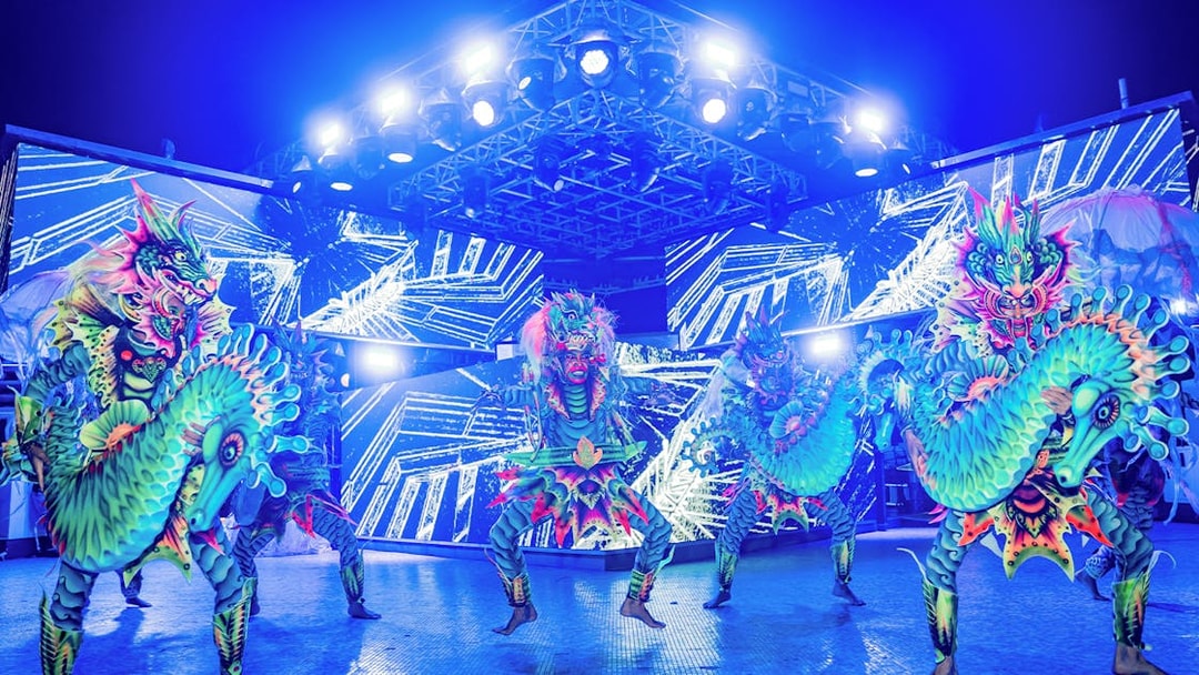 Performers in vibrant dragon costumes at Atlas Beach Club event.