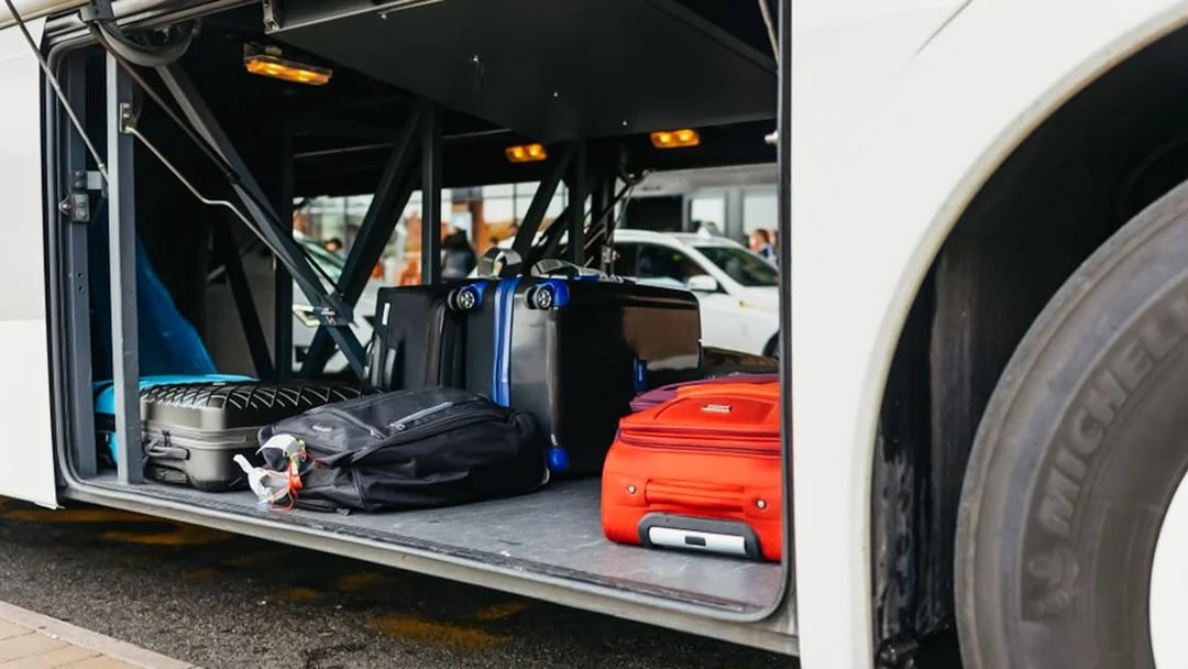 Luggage stored in the compartment of an airport transfer bus.