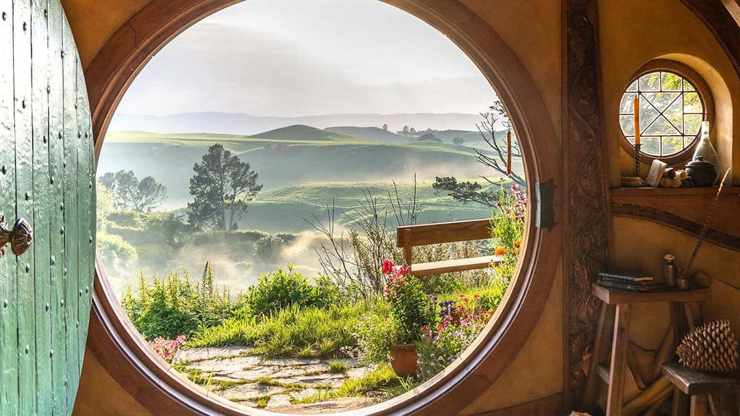 View from Hobbiton house window overlooking lush green hills in New Zealand.
