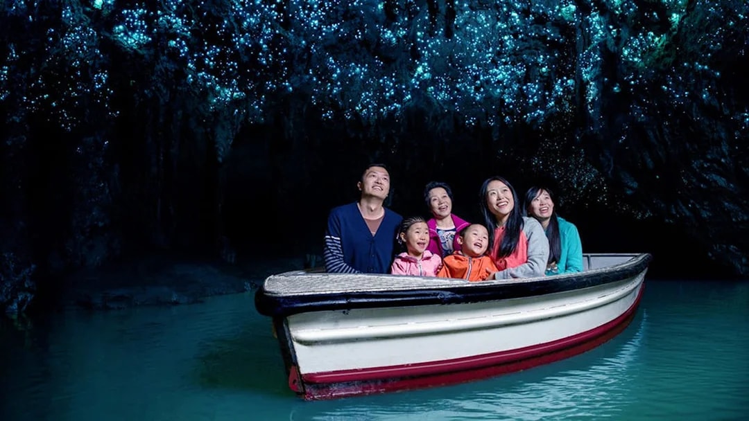 Group enjoying boat tour under glowworms in Waitomo Caves, New Zealand.
