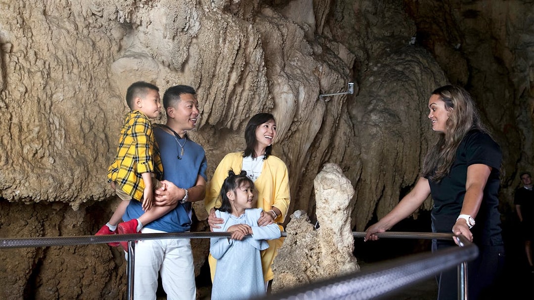 Family exploring Waitomo Caves with a guide, part of the Auckland Hobbiton Movie Set tour.