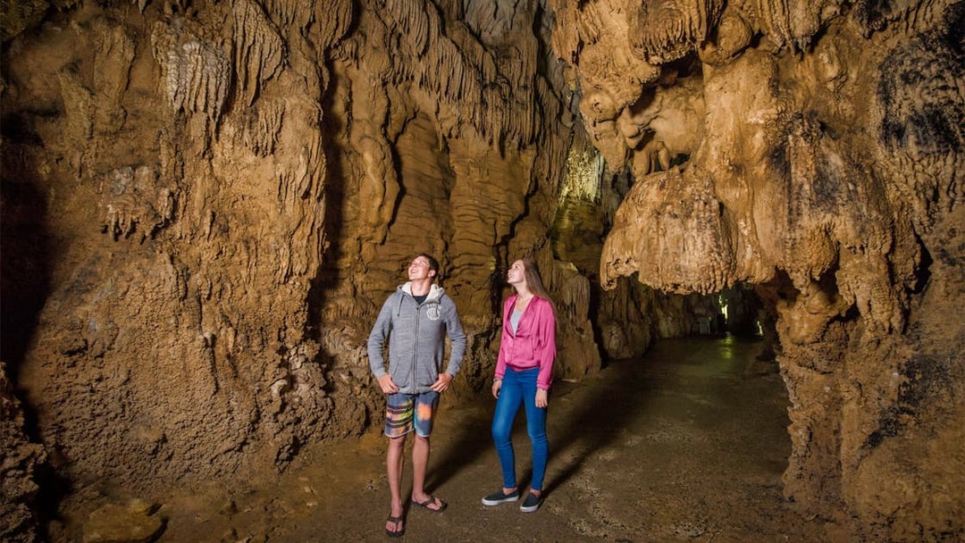 Tourists exploring stalactites in Waitomo Caves, Auckland, New Zealand.