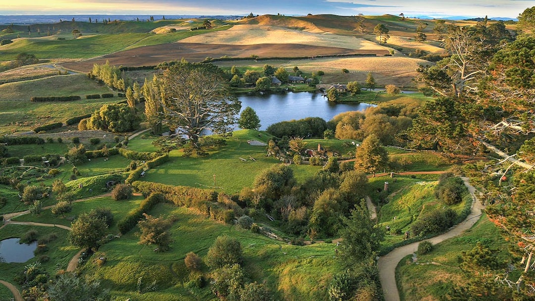 Hobbiton Movie Set with lush green hills and round doors, New Zealand.