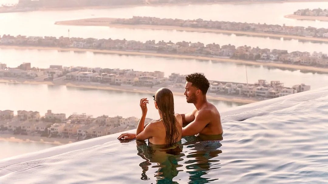 Couple enjoying the view from AURA Sky Pool overlooking Palm Jumeirah, Dubai.