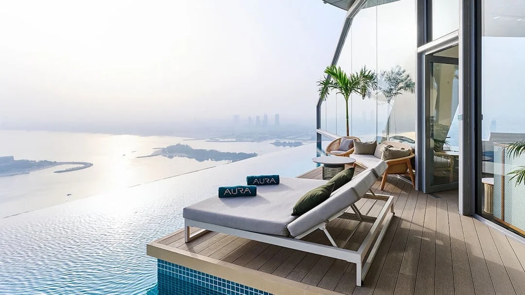 Sun loungers by the infinity pool at Rise at AURA Sky Pool, overlooking the city skyline.