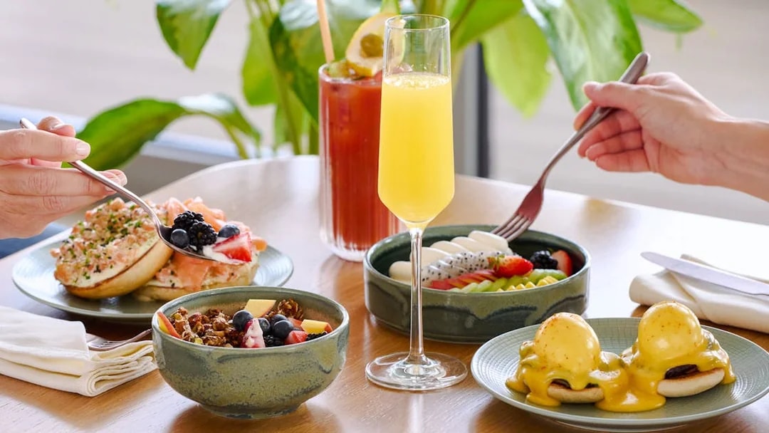 Brunch spread with eggs benedict, fruit bowls, and mimosas at Aura sky pool.