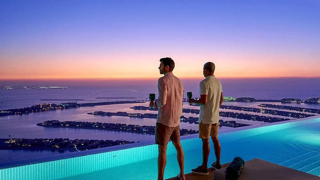 Tourists enjoying sunset view of Palm Jumeirah from Aura Sky Pool, Dubai.