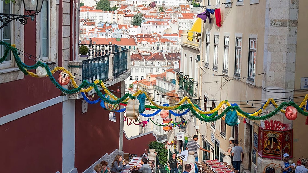 Lisbon street with colorful decorations and outdoor dining tables during a food and wine walking tour.