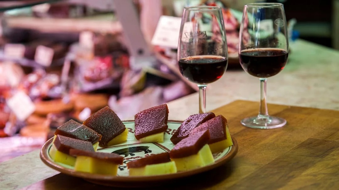 Cheese and quince paste with two glasses of red wine on a Lisbon food tour.