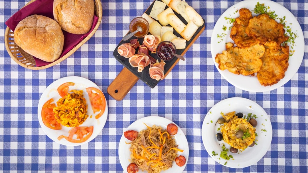 Portuguese dishes and bread on a checkered tablecloth during Lisbon food and wine tour.