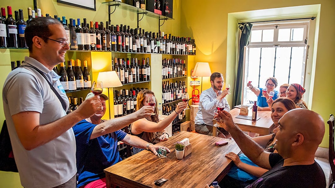 Group enjoying wine tasting in a Lisbon wine shop during a food and wine walking tour.