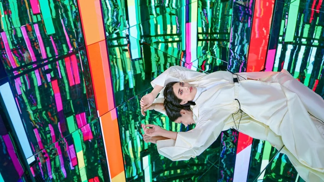 Woman in white outfit at Tides zone, AYA universe, Dubai with colorful reflections.