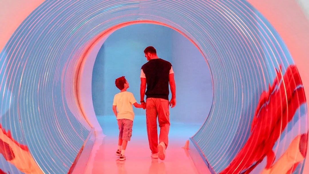 Man and child walking through a colorful tunnel at AYA Universe, Dubai.